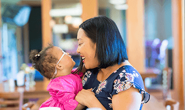 An RMHC family, the Burrells, mom Lindsey holding infant Piper, smiling at one another