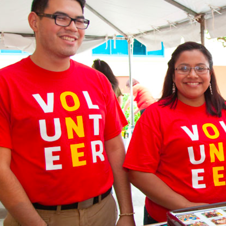 Volunteers fundraising for RMHC outdoors under a tent at a public event.