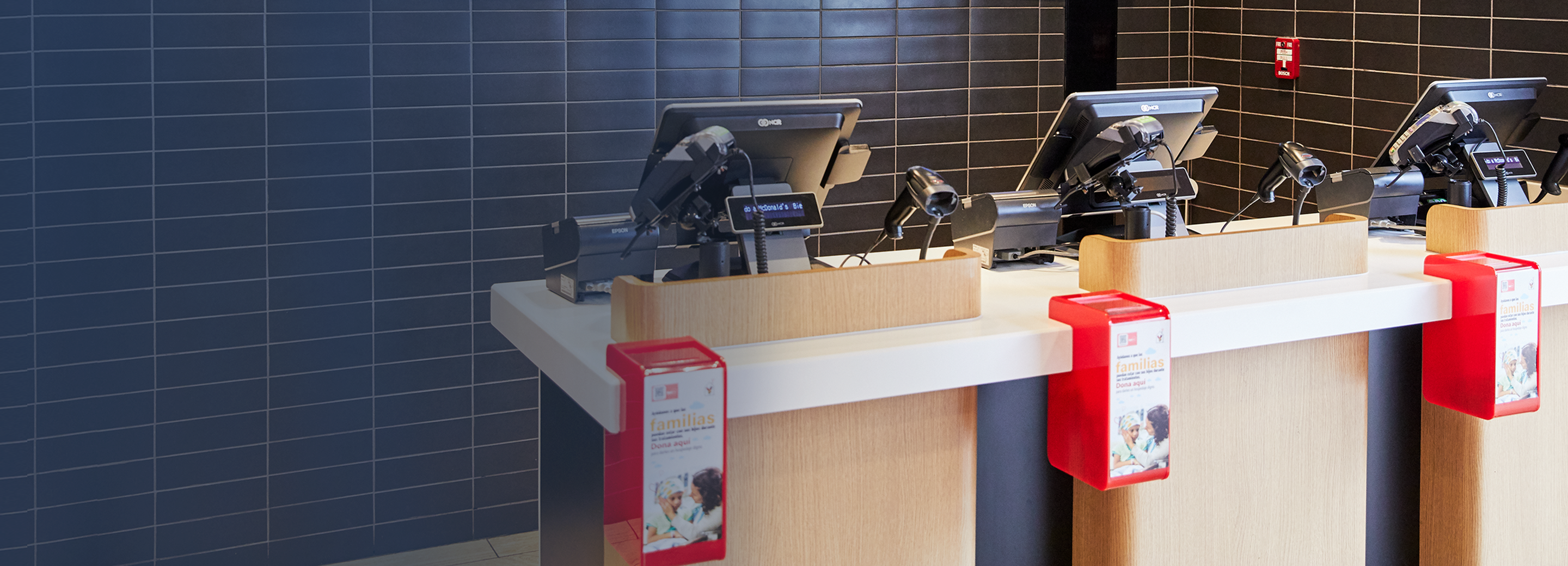 Angled photo of red RMHC donation boxes in front of McDonald's registers