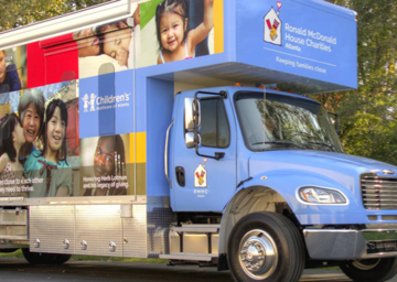 A parked Care Mobile against a background of trees, vehicle wrapped in RMHC family imagery and messaging, RMHC Atlanta