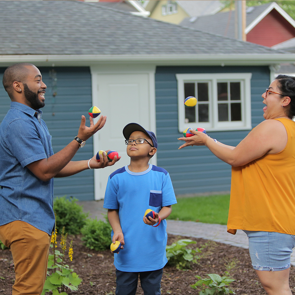 An RMHC family, dad, son, and mom, juggling in their yard, supporting a Raise Love fundraiser