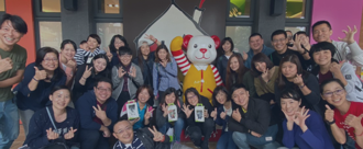Link background, a group of volunteers smile for the camera outside local a Ronald McDonald House program, posing with anthropomorphized Ronald McDonald mouse 