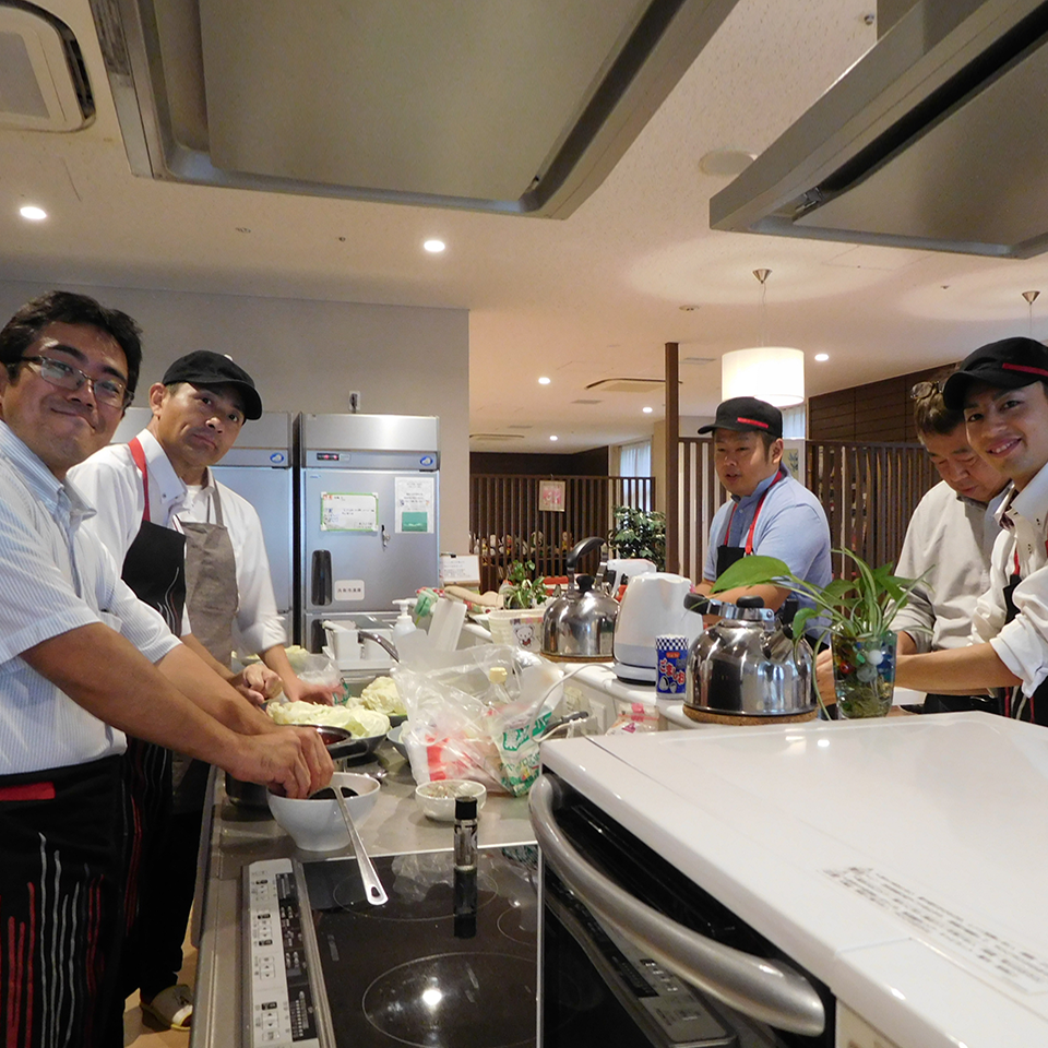 Four volunteers prepping and cooking food in an open kitchen