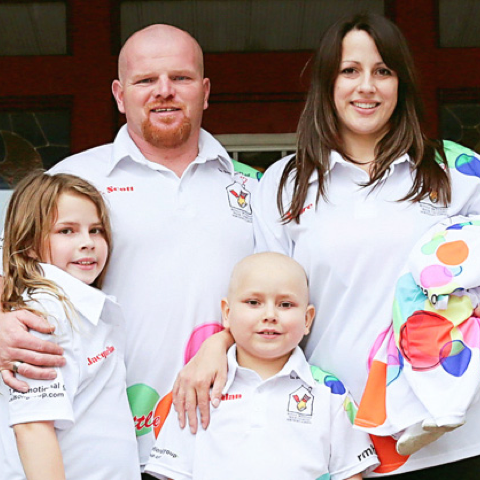 An RMHC family in matching white RMHC polo shirts, dad and mom in back row, children in front