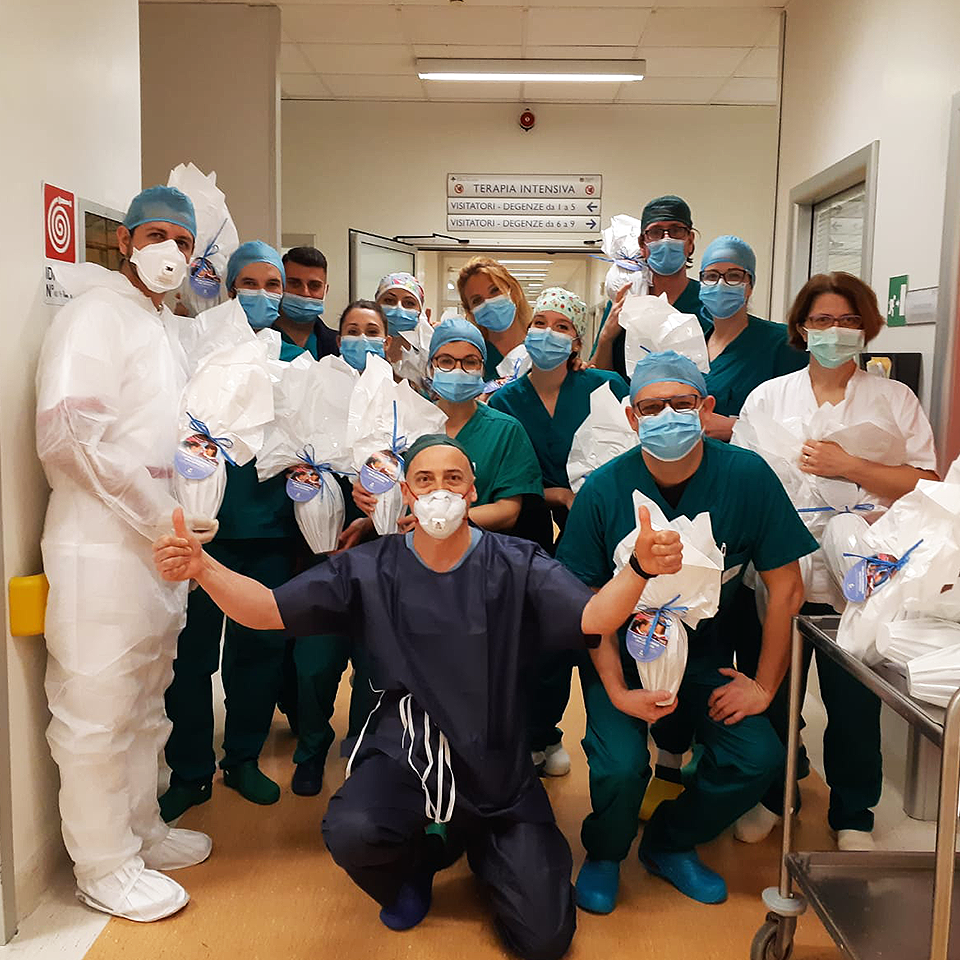 Masked staff in a medical facility hallway, posing for the camera holding wrapped RMHC gift baskets